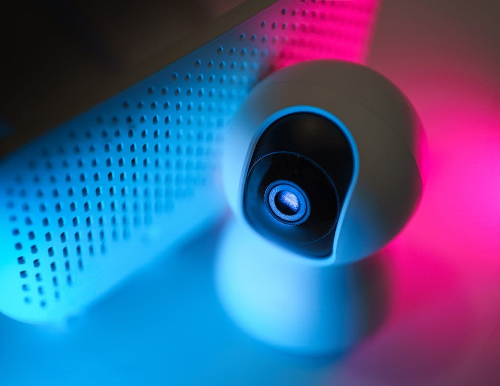 Close-up of a surveillance camera with neon lighting, symbolizing modern home security technology.